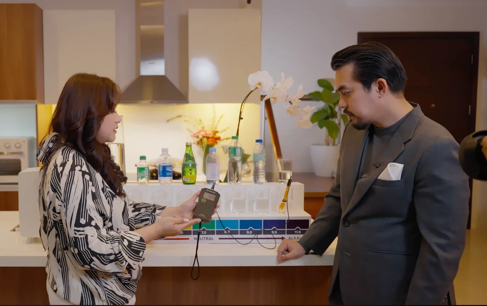Two people testing water quality at a kitchen island in a modern home