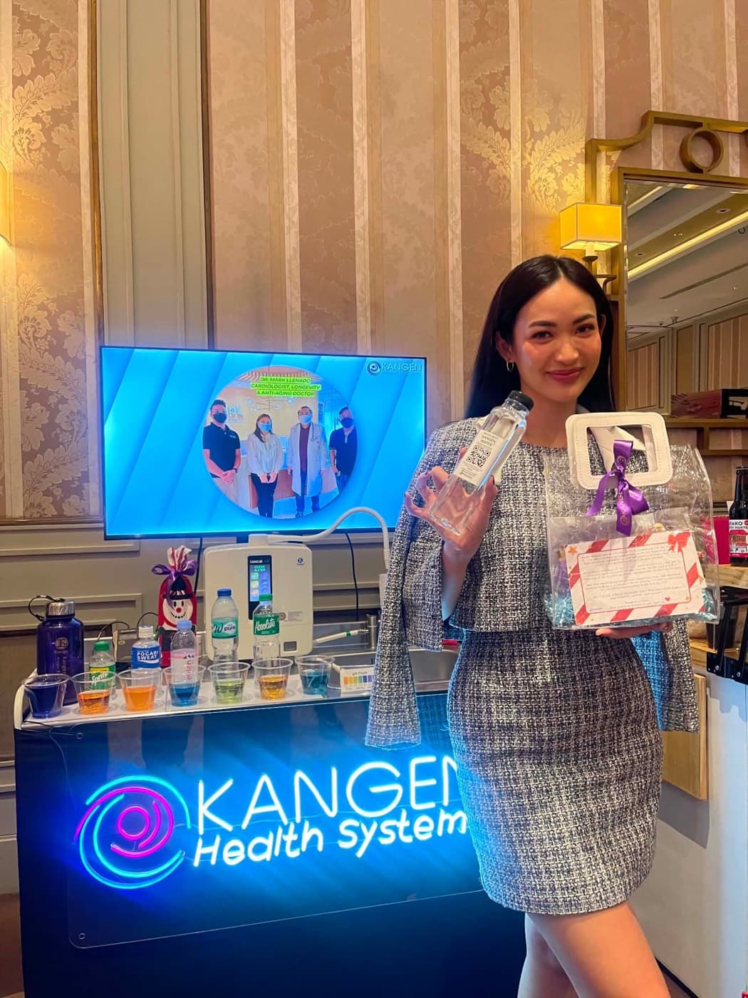 A woman holding a bottle of Kangen water at a Kangen Health System demonstration counter