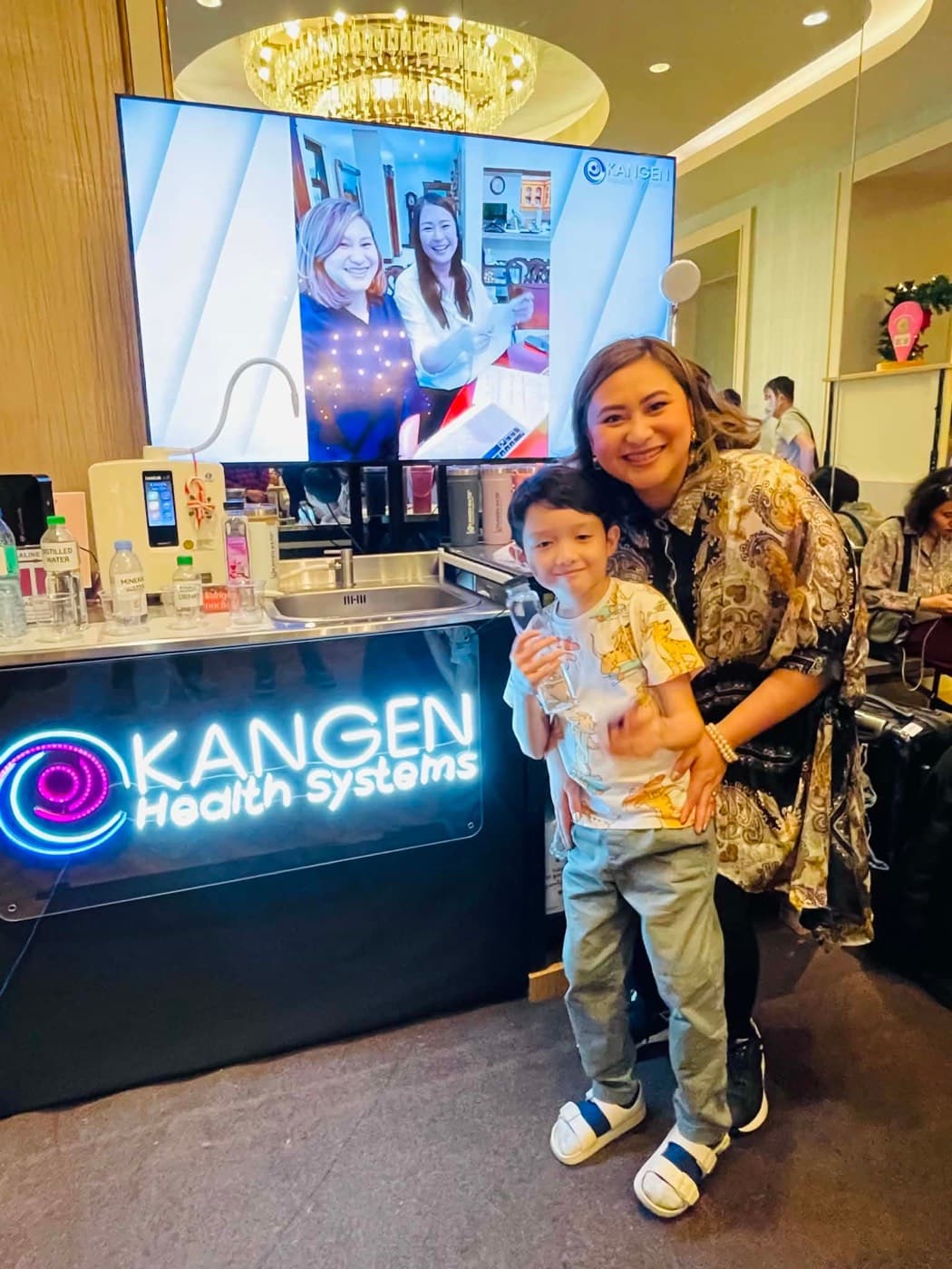 A woman and a child at a Kangen Health System demonstration booth