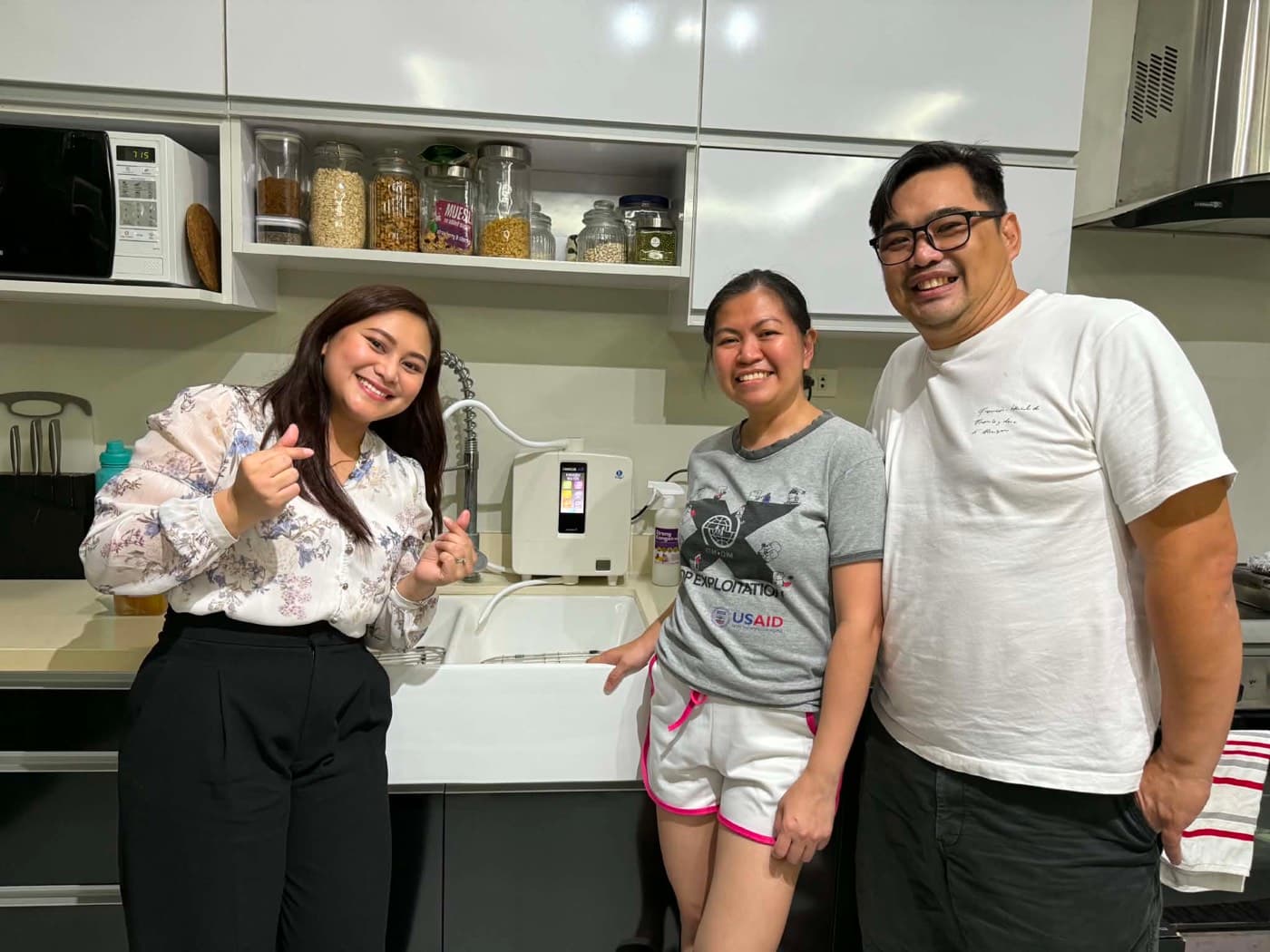 Three people beside a Leveluk K8 hosed to the kitchen tap
