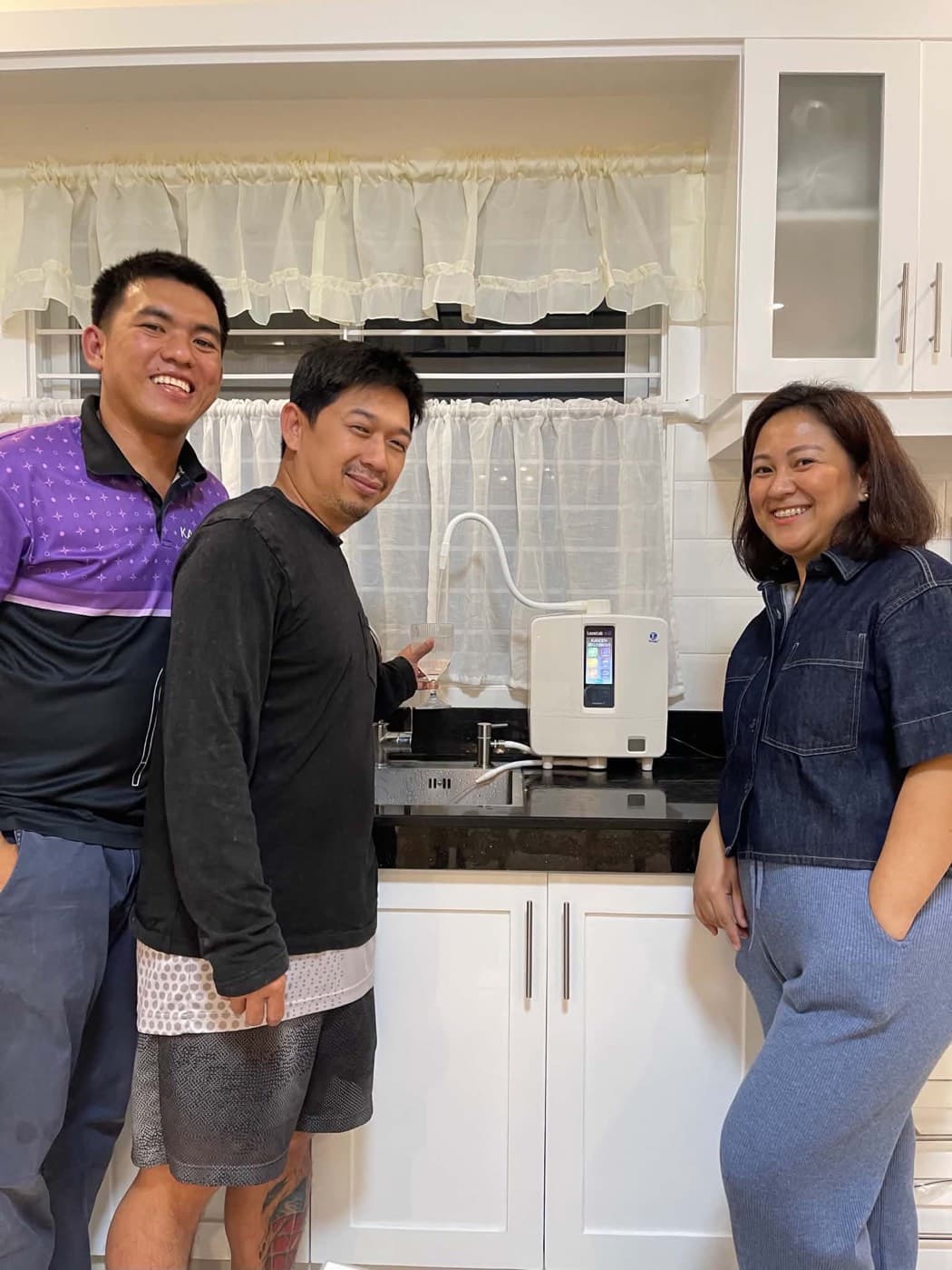 Three people beside a newly installed Leveluk K8 on a black granite counter