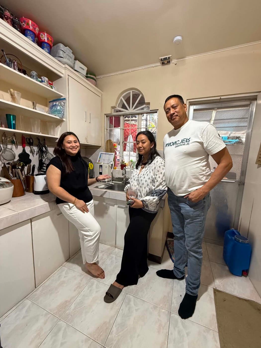 Three people around a Leveluk K8 installed beside the sink, its hose run to the tap