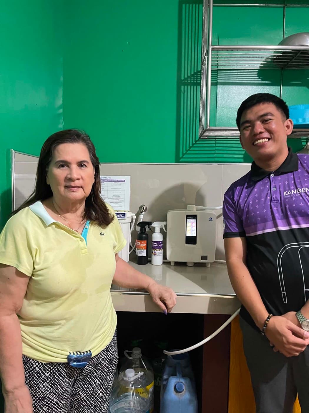 Two people either side of a Leveluk K8 in a green-walled kitchen